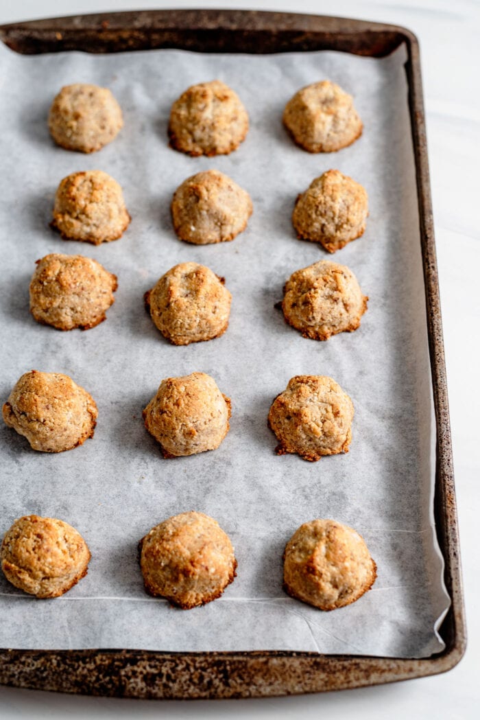 Baked coconut macaroons on a baking tray lined with parchment paper.