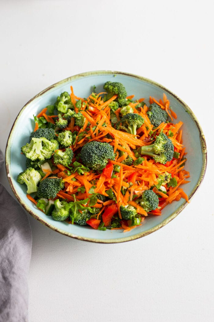 Bell pepper, cucumber, carrot, broccoli and cilantro mixed together in a bowl.