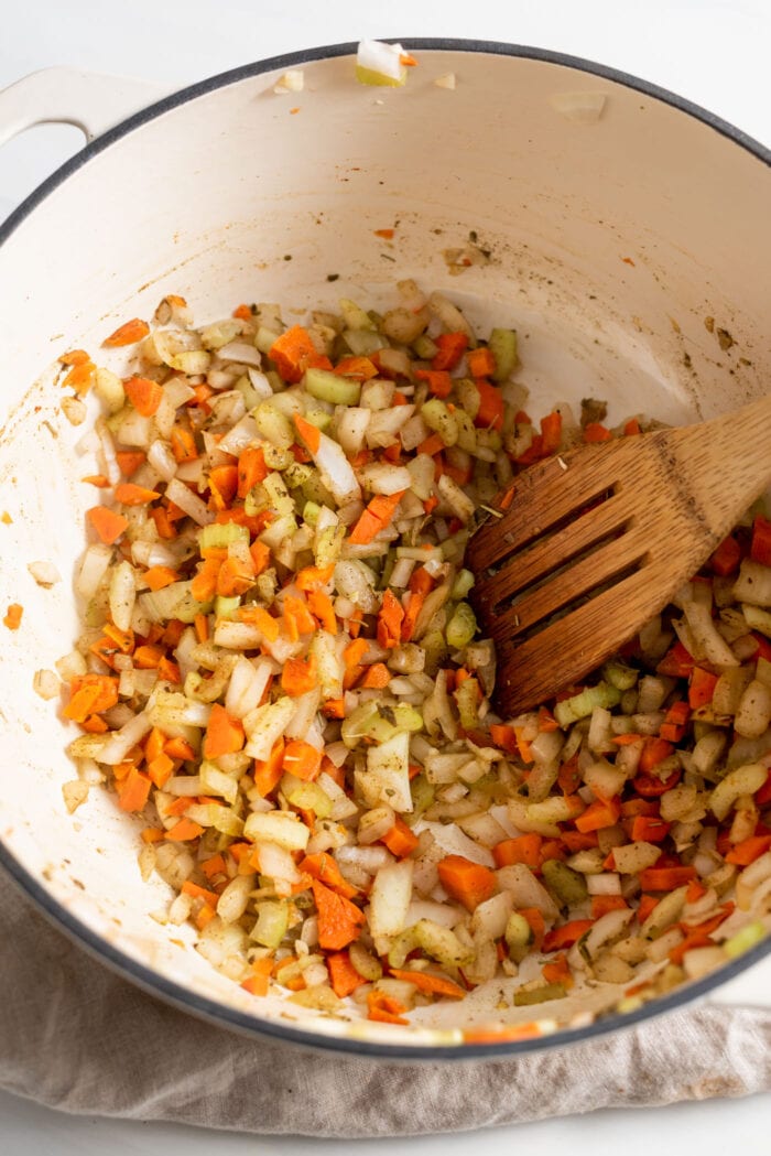 Diced carrot, onion, celery and garlic with dried herbs cooking in a large soup pot.