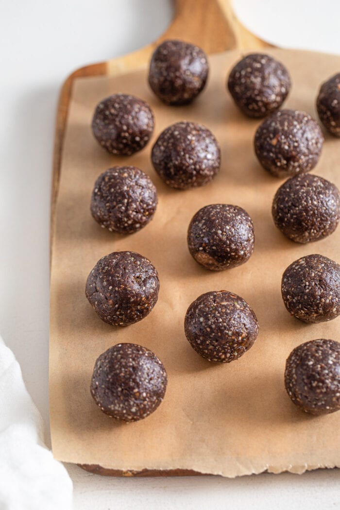 Chocolate energy balls on a cutting board lined with parchment paper.