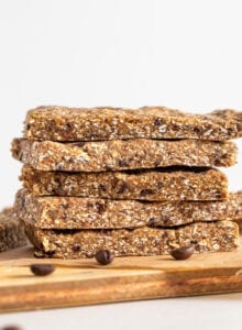Stack of 4 energy bars on a cutting board. Coffee beans scattered around.