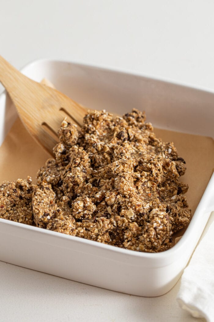Raw coffee energy bar dough in a baking pan lined with parchment paper.