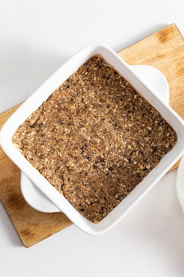 Energy bars in a ceramic baking dish with handles, sitting on a cutting board.