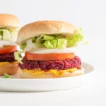Two beet burgers on buns with onion, lettuce and tomato.