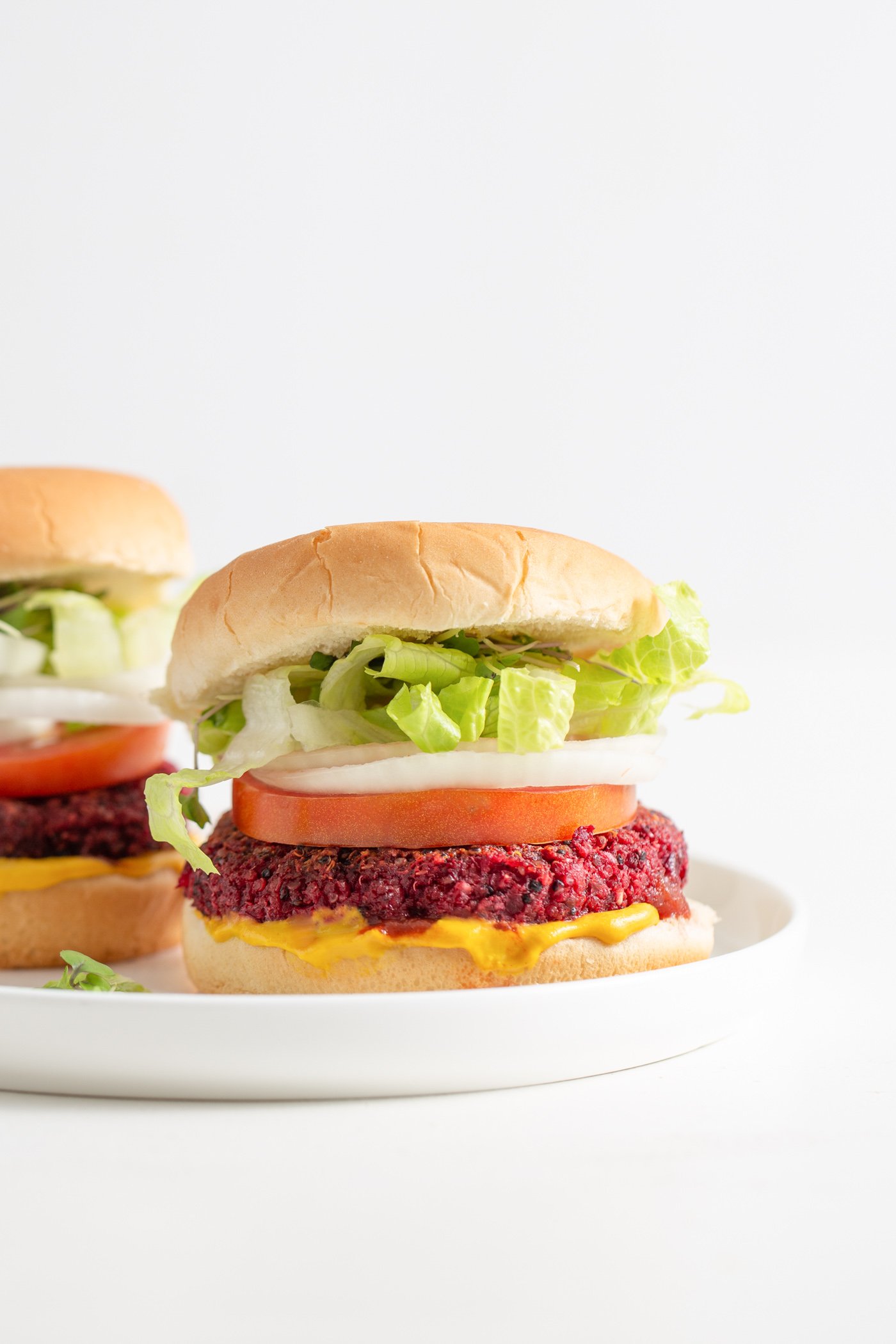 Two beet burgers on buns with onion, lettuce and tomato.