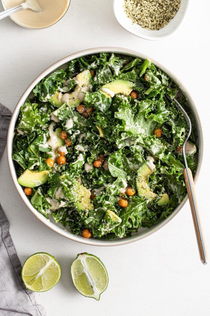 A bowl of kale salad with chickpeas, avocado and hemp seeds in a creamy dressing.