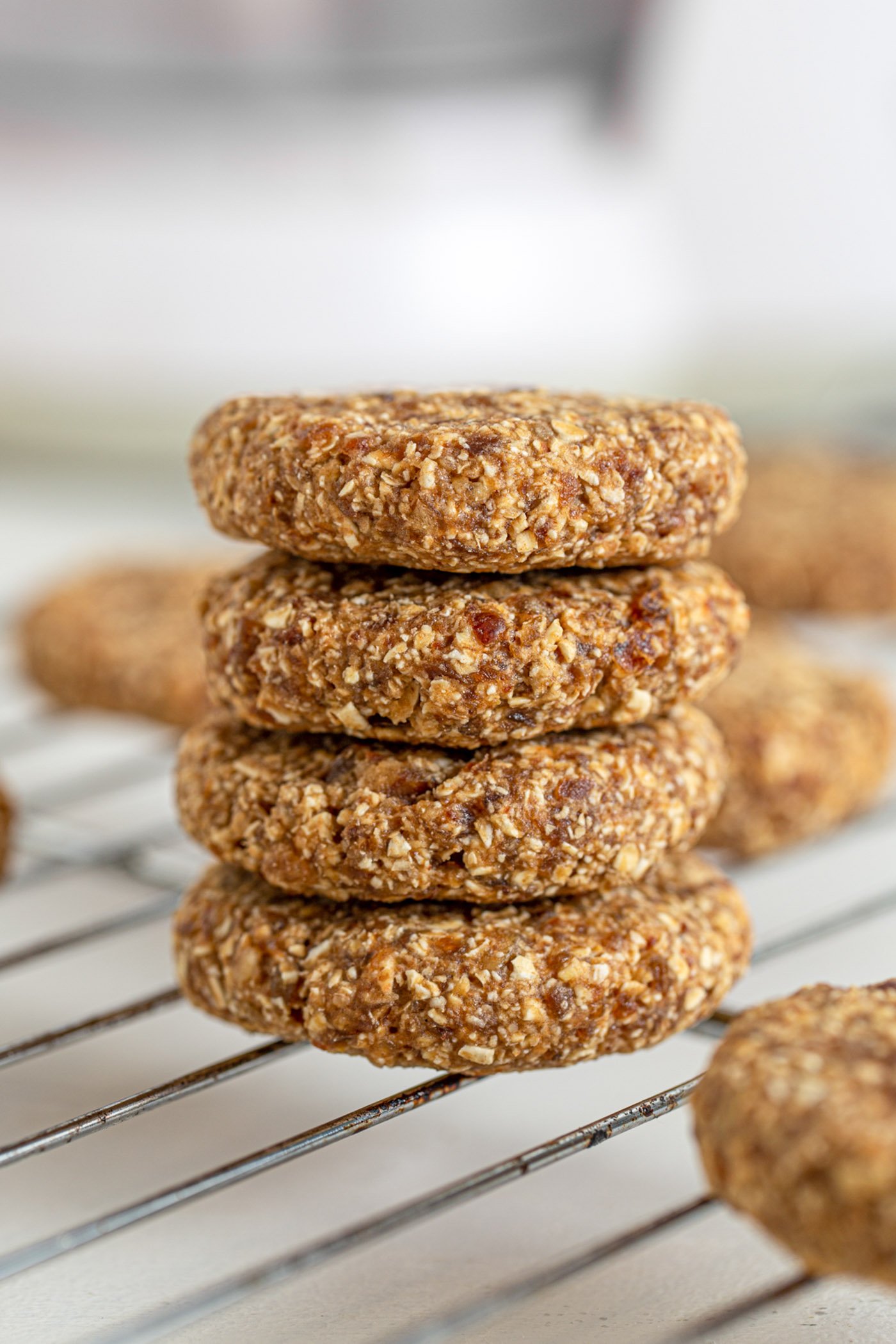 Stack of 4 tahini date cookies sitting on a cooling rack.