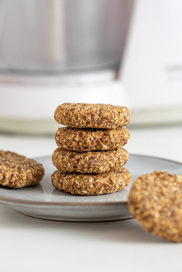 Stack of 4 tahini oat cookies on a plate. 2 cookies rest beside the stack on the plate.