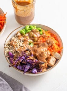 Bowl of cabbage, rice, tofu, carrot, edamame. Topped with creamy peanut sauce.