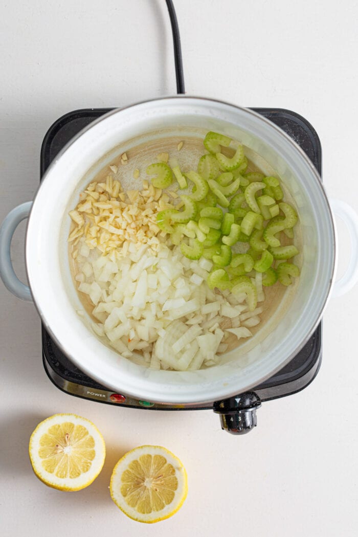 Onion, garlic and celery cooking in a soup pot.