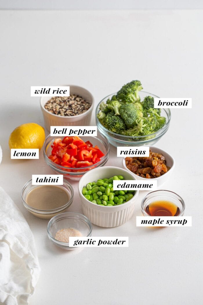 Rice, broccoli, lemon, tahini, edamame, maple syrup, raisins and chopped bell pepper in bowls. Labelled with text overlay.