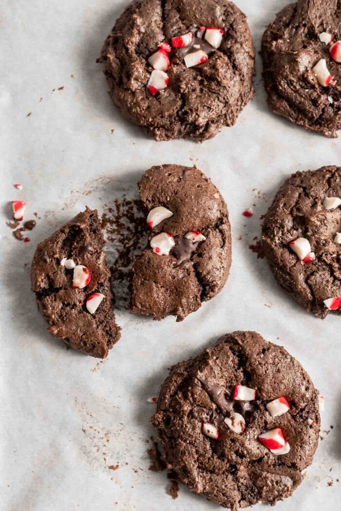 Chocolate cookies topped with crushed candy canes on a baking tray.