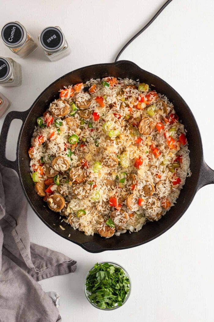 Rice, bell peppers and various spices cooking in a skillet.