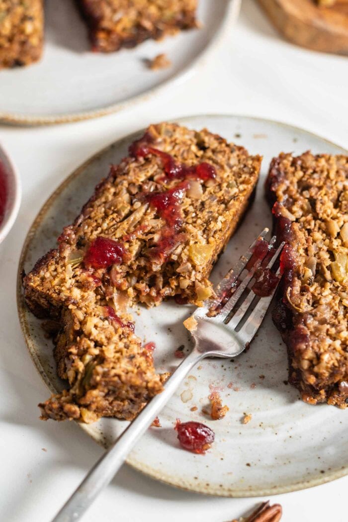 Two slices of vegan nut roast topped with cranberry sauce on a small plate.