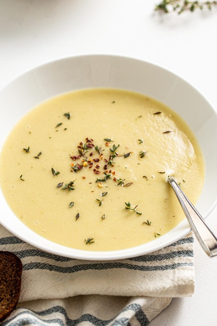 Creamy potato leek soup in a bowl topped with rosemary and red pepper flakes.