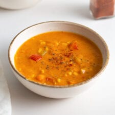 Bowl of sweet potato corn chowder. Another bowl of soup in background.