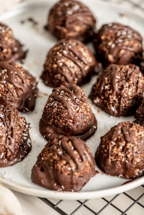 Close up of chocolate coconut macaroons on a white plate sitting on a cooling rack.