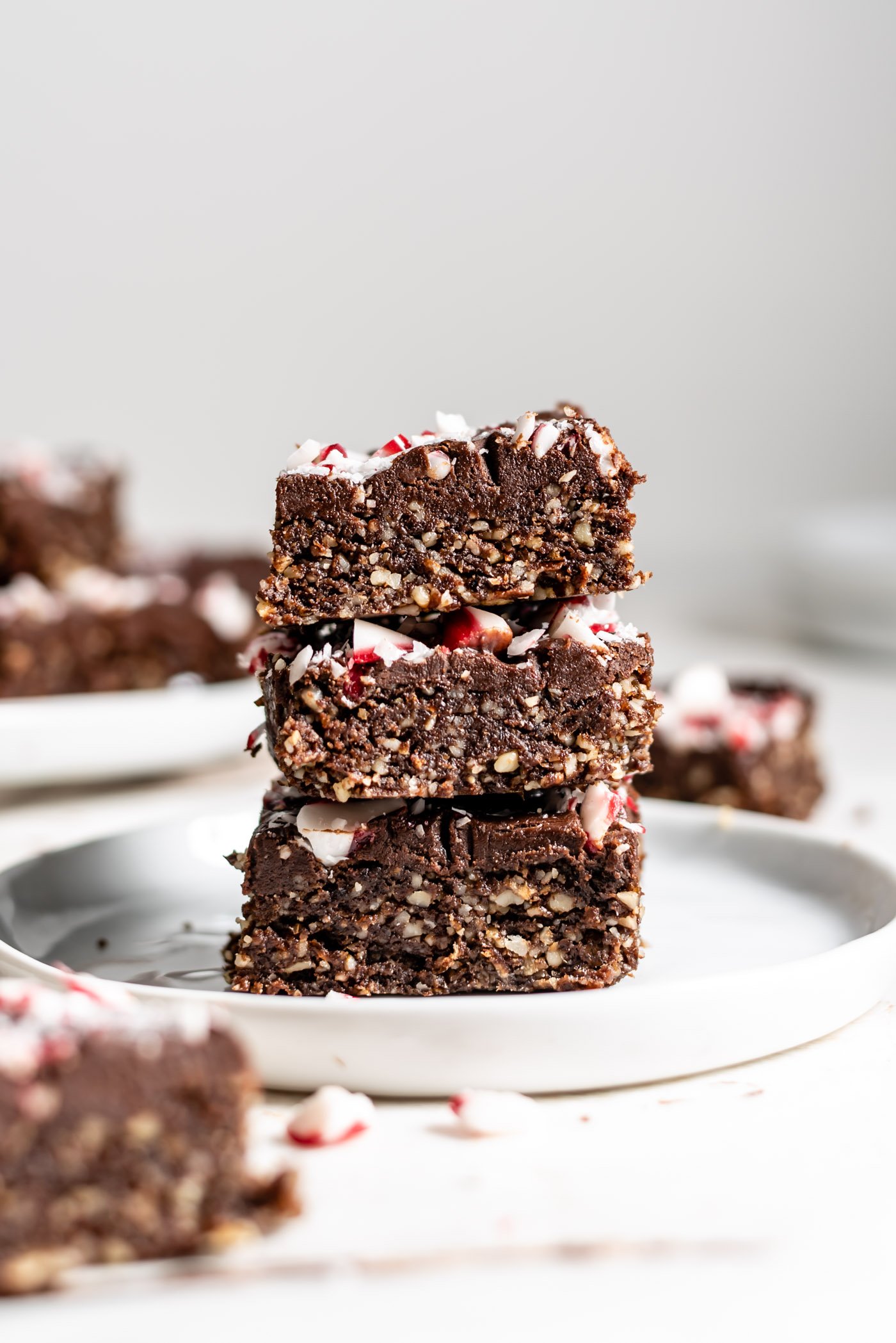 Stack of 3 vegan peppermint brownies topped with ganache and candy canes.