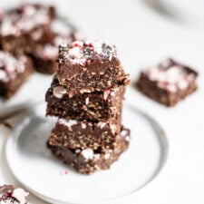 Stack of 4 peppermint brownies topped with crushed candy canes on a small plate.