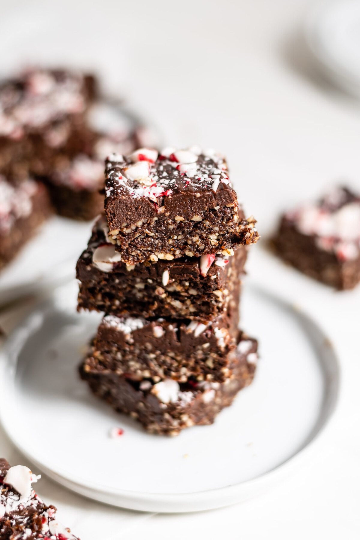 Stack of 4 peppermint brownies topped with crushed candy canes on a small plate.