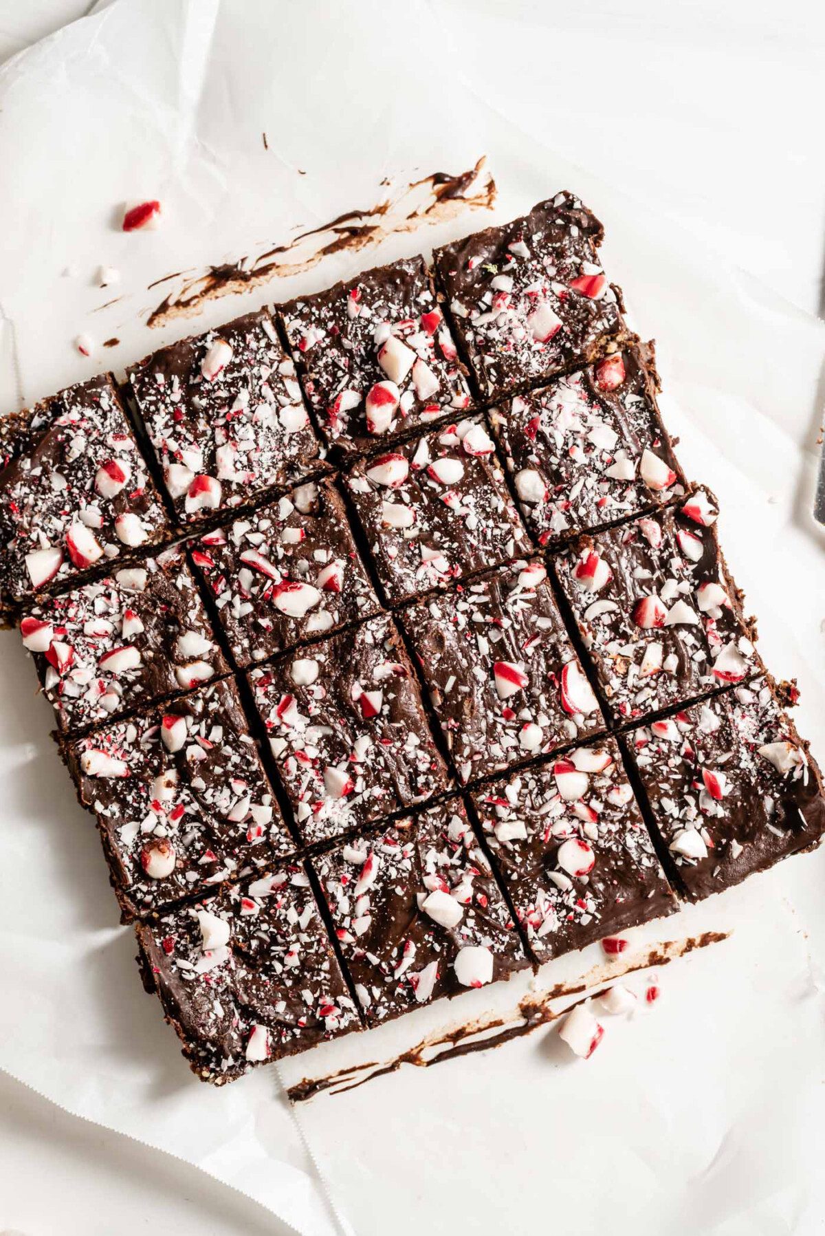 Tray of peppermint brownies sliced into 16 portions on a piece of parchment paper.