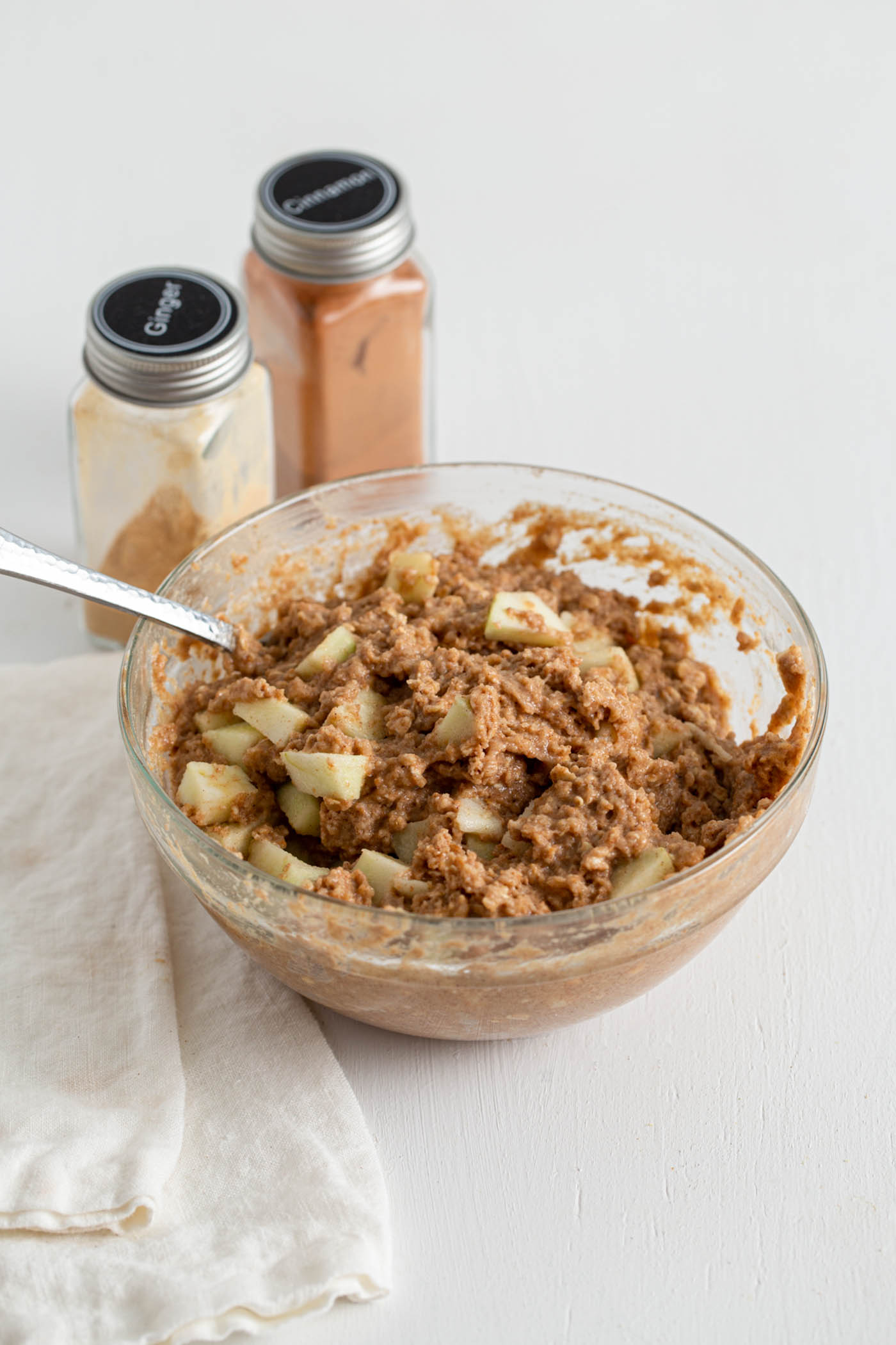 Muffin batter with diced apple mixed into it in a mixing bowl.