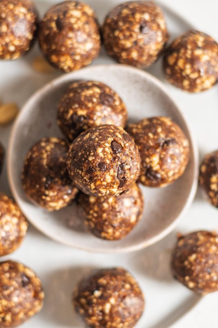 Overhead image of a plate of no-bake date energy balls with peanuts and chocolate chips.