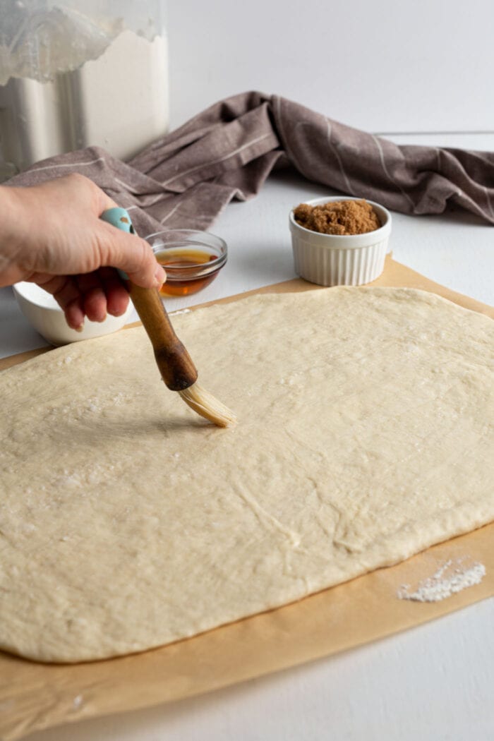 Brushing rolled dough with melted butter.