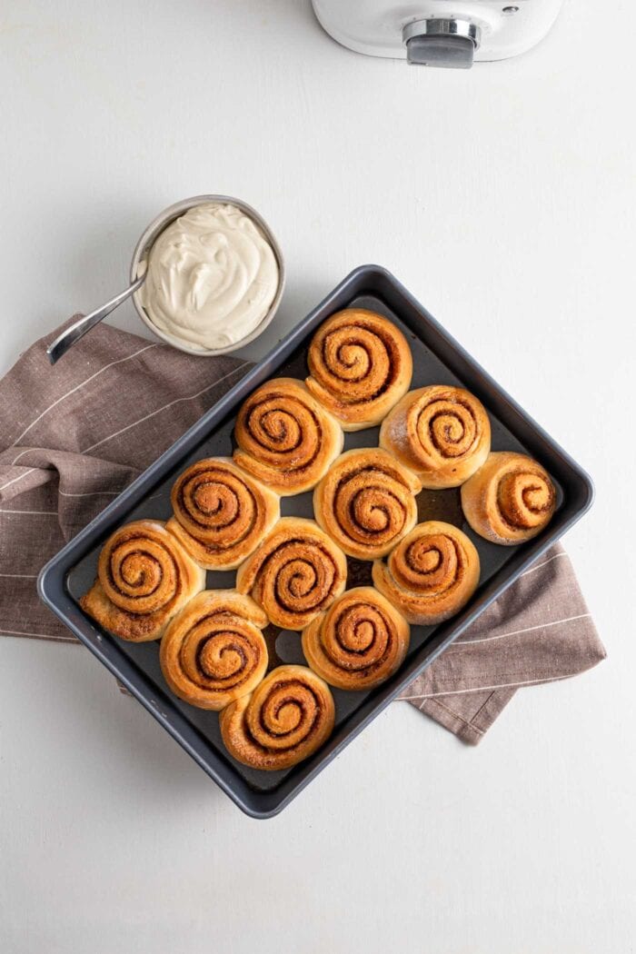 Overhead view of 12 baked cinnamon buns in a baking dish.
