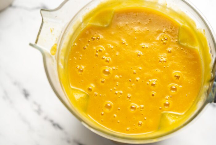 Creamy squash soup in a blender container.