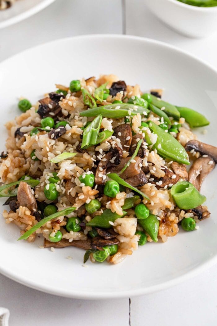 Plate of Chinese mushroom fried rice topped with sesame seeds and spring onions.
