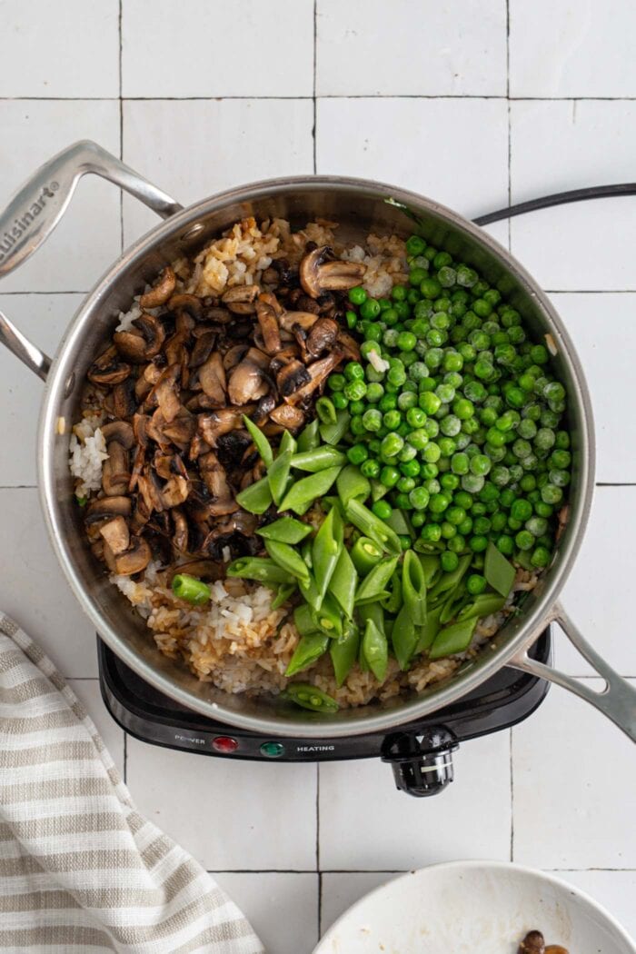 Snap peas, mushrooms and green peas cooking in a skilet.