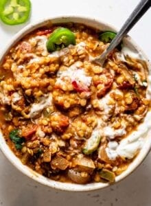 Overhead view of a a bowl of lentil chili with sour cream and jalapeños on top.