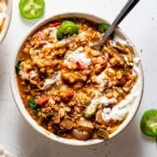 Overhead view of a a bowl of lentil chili with sour cream and jalapeños on top.