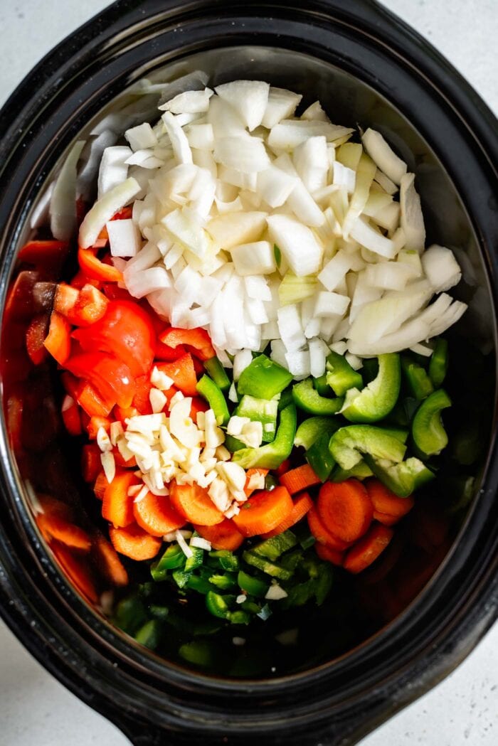 Chopped onion, bell peppers, carrot, jalapeno and garlic in a crockpot.