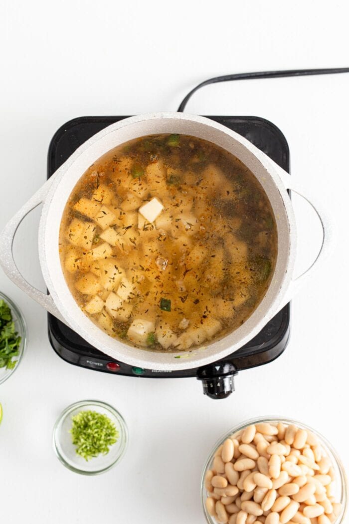 Diced potatoes cooking in broth in a large soup pot.