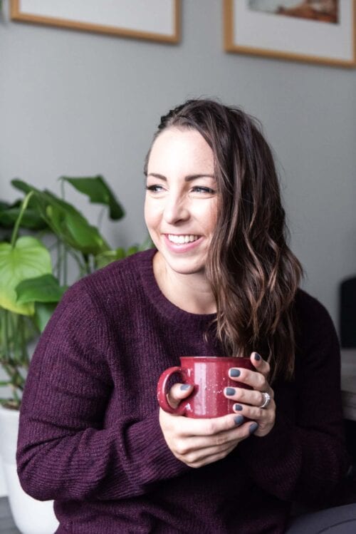 Woman looking out window holding a coffee cup.