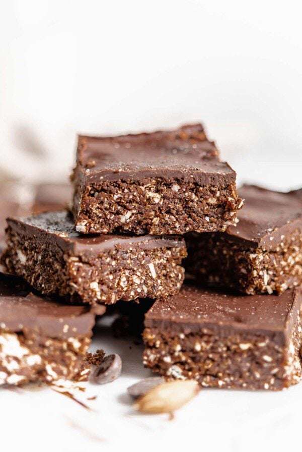 Stack of chocolate-topped chocolate square on a piece of parchment paper.