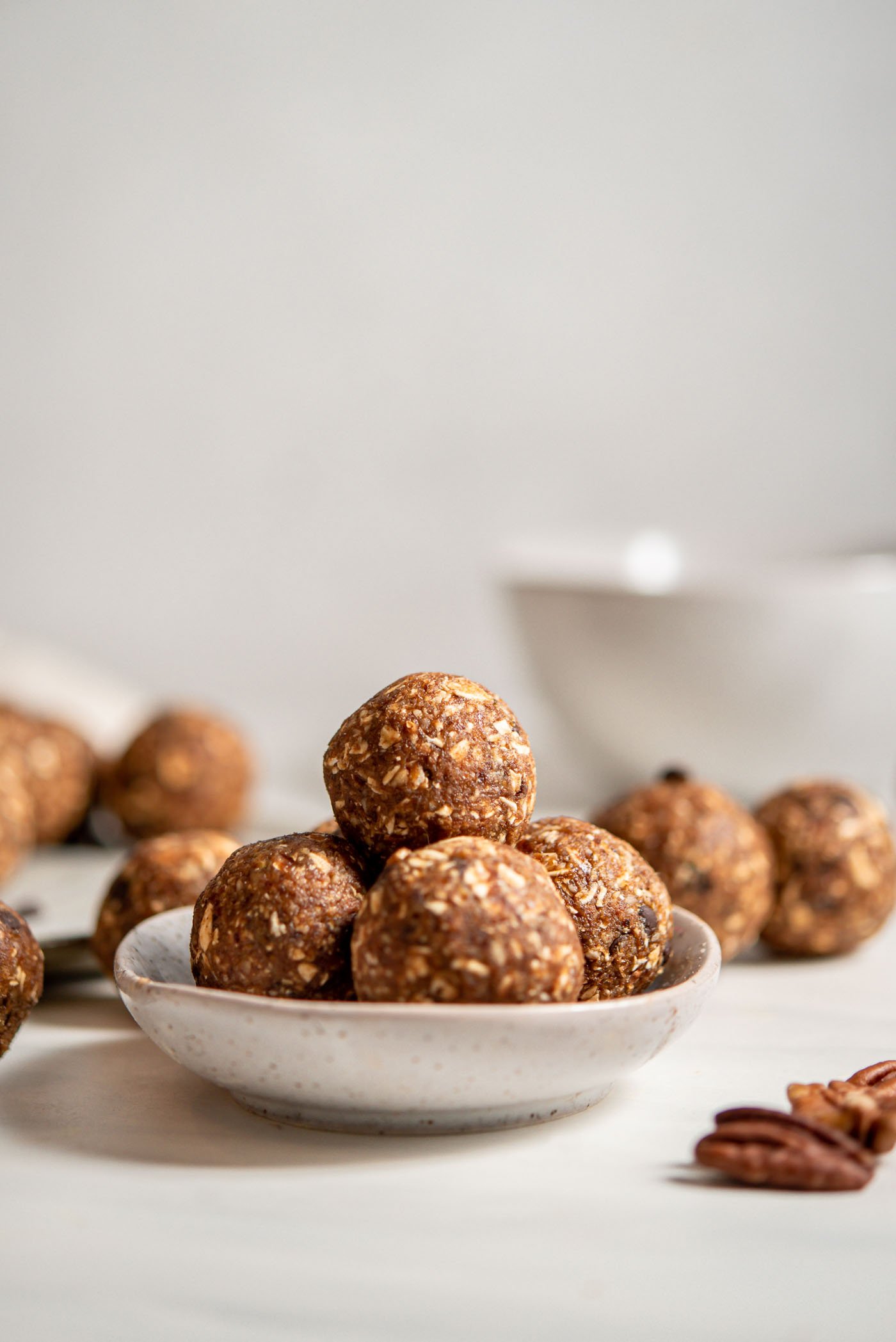 A few raw banana bread energy balls in a small dish. More balls in background.