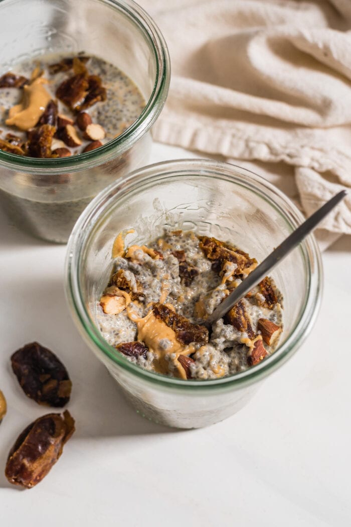 Two jars of chia pudding with peanut butter, almonds and dates.