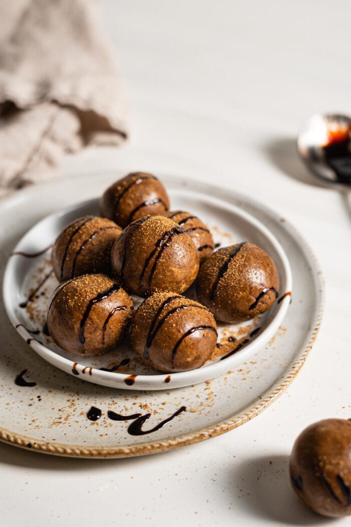 Gingerbread energy balls drizzled with molasses on a small plate.