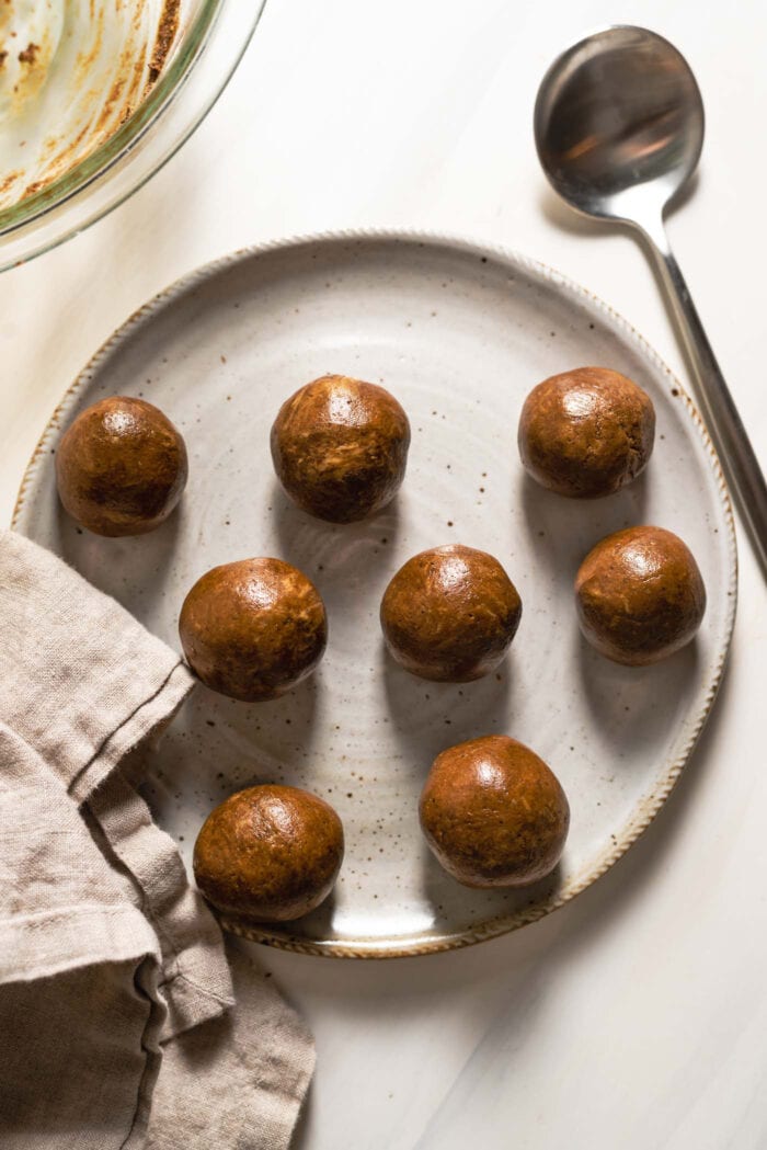 Raw gingerbread cookie dough balls on a plate.