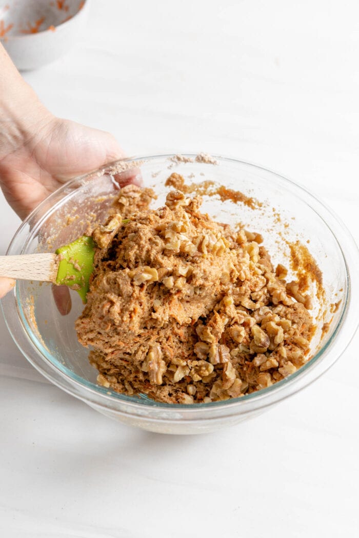 Folding chopped walnuts into batter in a large mixing bowl.