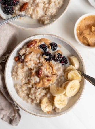 Bowl of oatmeal topped with peanut butter, banana and berries.