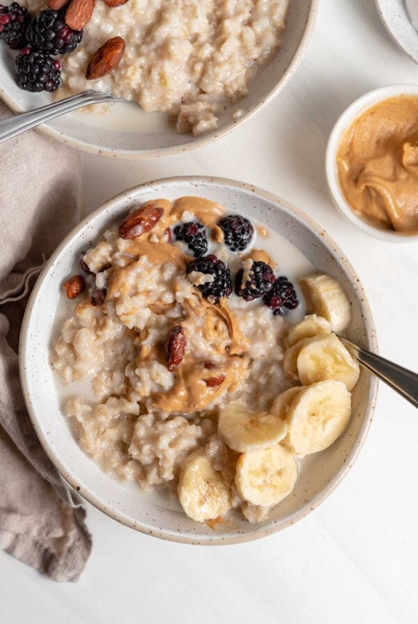 Bowl of oatmeal topped with peanut butter, banana and berries.