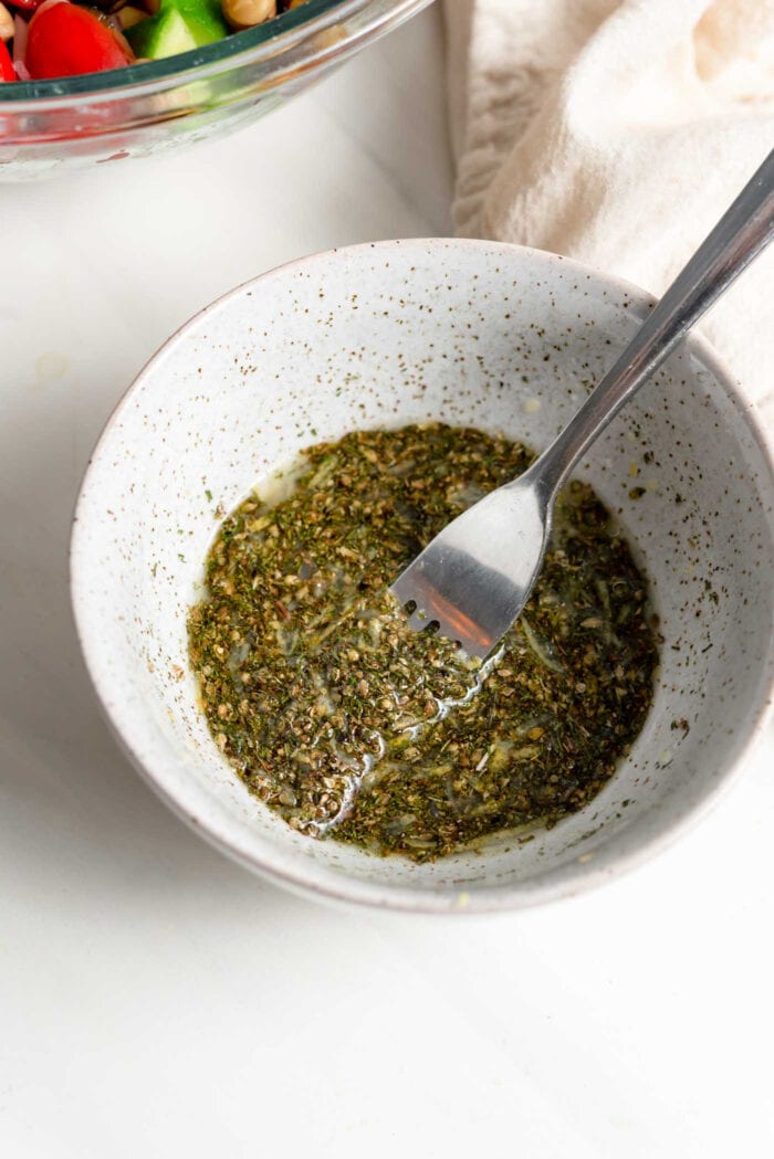Herb salad dressing mixed in a small bowl with fork.