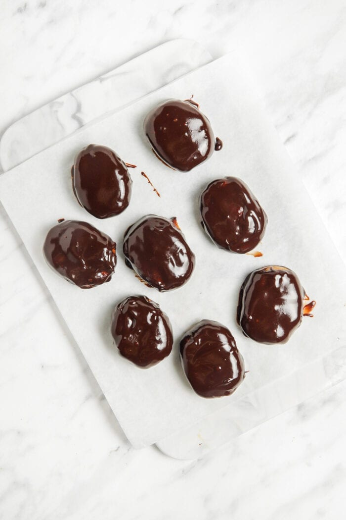 12 chocolate peanut butter eggs sitting on a piece of parchment paper.