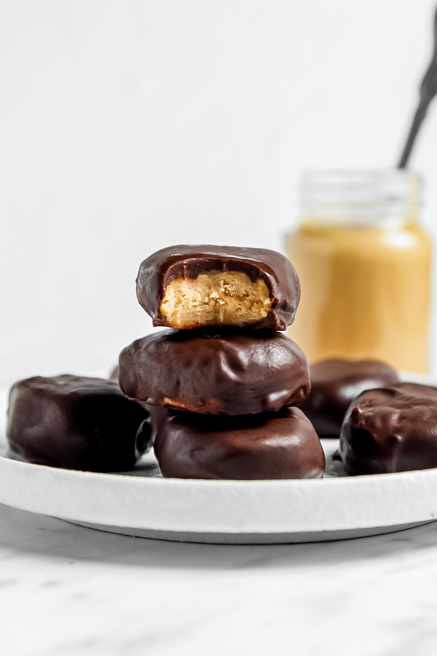 Stack of 3 peanut butter eggs on a plate, one on top with a bite out of it to show the texture inside.