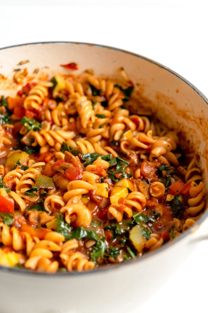 Rotini pasta in a pot with vegetables and sauce.