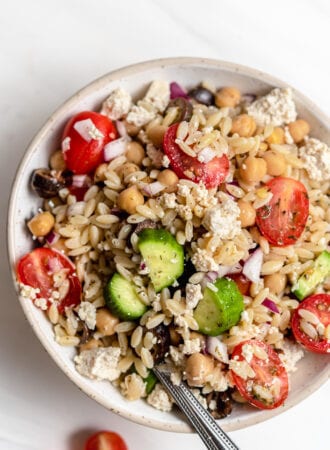 Overhead view of bowl of Mediterranean orzo salad with tomato, cucumber and olives.